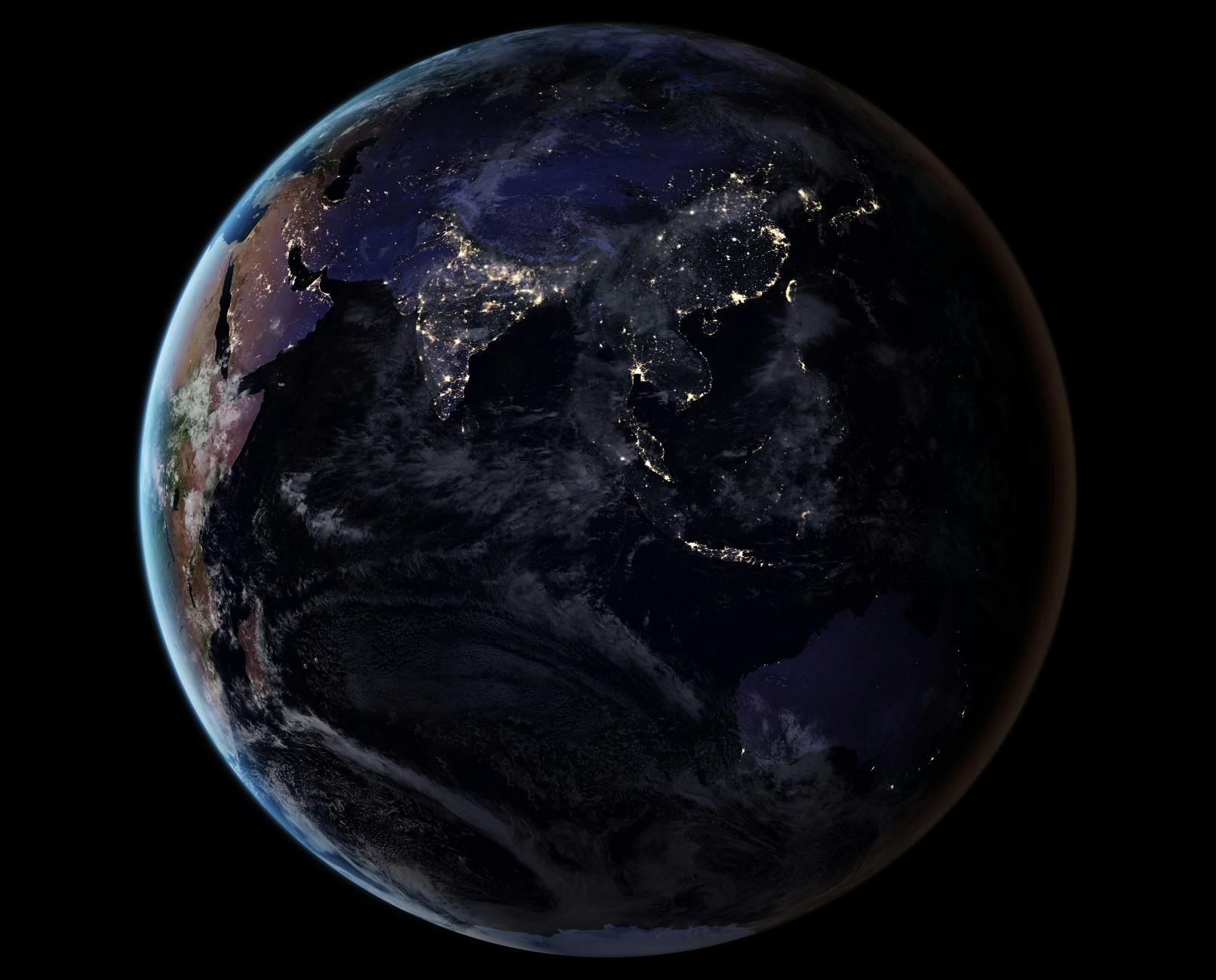 Earth from space in the night time, with visible light coming from human cities pockmarked on Earth